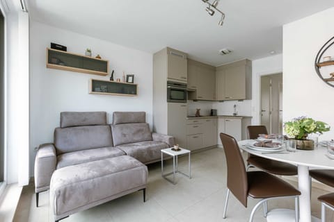 Modern open-plan living area with a compact kitchen and dining table set for four.