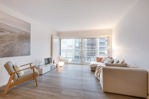 Bright living room with modern seating and large windows overlooking the city.