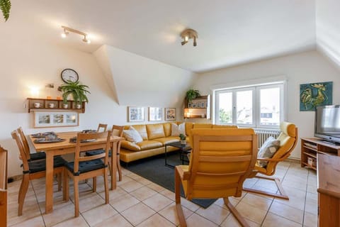 Bright living room with mustard leather seating and a dining area by the window