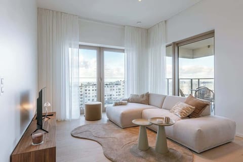 Modern living room with a large sectional sofa and balcony views.