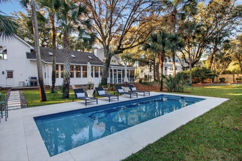 Resort‑style pool with loungers, umbrellas, and a peaceful backyard setting.
