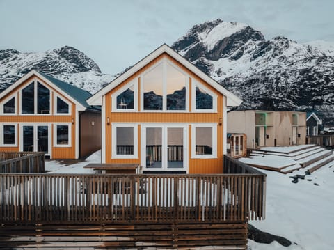 The front view of a charming yellow cottage designed in classic Lofoten style with a modern twist.