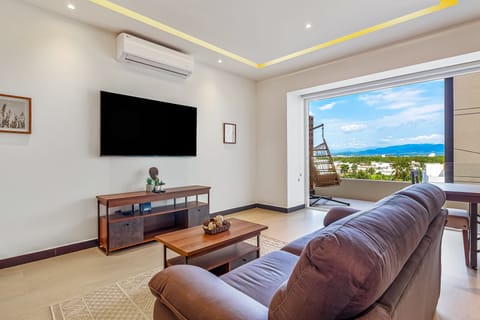 Relax on the comfortable sofa in this modern, air-conditioned living room featuring a flat-screen TV and large sliding doors that lead out to the balcony.