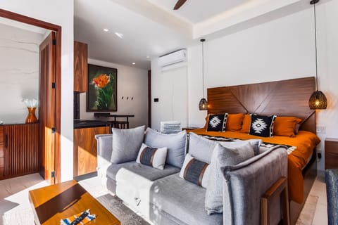 Integrated studio space featuring a comfortable grey sofa, coffee table, and an inviting bed.