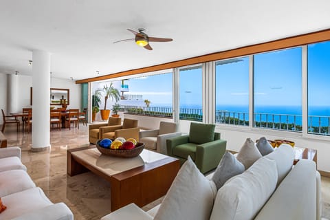 Bright living space with plush seating, floor-to-ceiling windows, and stunning ocean views—perfect for relaxing or entertaining.