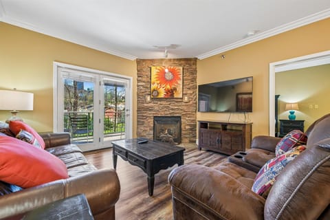 Sink into plush leather seating by your cozy stone fireplace, where warm golden walls and mountain views create the perfect retreat.