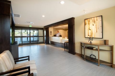 Front desk reception with floor-to-ceiling glass entry doors and a welcoming seating area