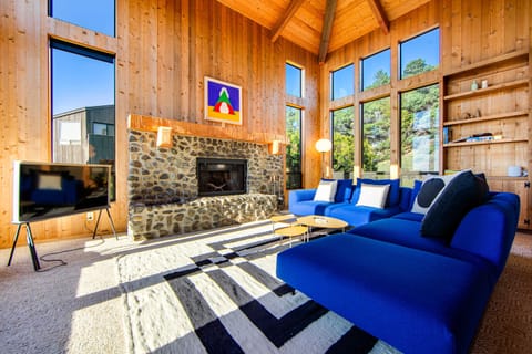 Relax on the plush blue sofa while enjoying views of the lush greenery outside, creating a perfect backdrop for your coastal getaway.