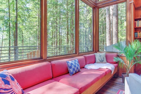 Curl up on the plush red sofa, where you can lose yourself in a good book while enjoying the lush forest views.
