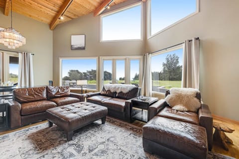 Gather with loved ones in this cozy living room, where floor-to-ceiling windows frame breathtaking coastal views.