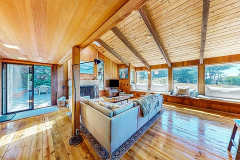 Gather around the wood-burning fireplace in this sunlit living area, perfect for cozy evenings with friends and family.