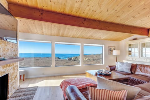 Morning light floods the living room, inviting you to relax and soak in panoramic ocean vistas from the comfort of plush seating and a non-operational decorative fireplace. 
