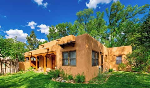 Classic Taos adobe wrapped in green lawn and old cottonwoods
