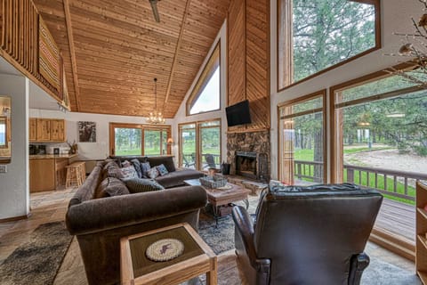 Relax in the soaring great room with a stone fireplace and forest views
