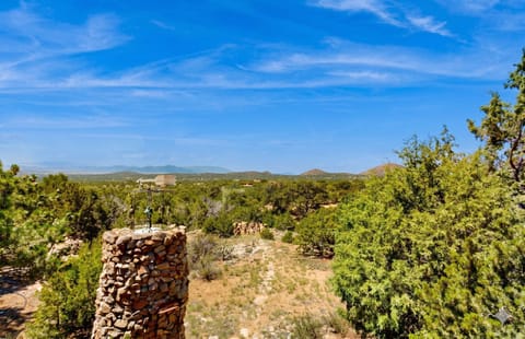 A rustic Pueblo-style home framed by piñon and high desert