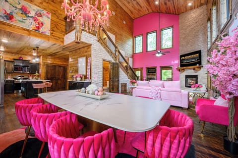 Step into a vibrant, open-concept space where pink hues and natural wood create a playful yet cozy retreat. You'll love the soaring ceilings, plush seating, and the inviting fireplace for those quiet evenings in.