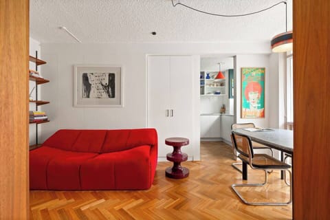 Bright, retro-inspired living space with cosy seating and a TV, flowing seamlessly to dining and balcony.