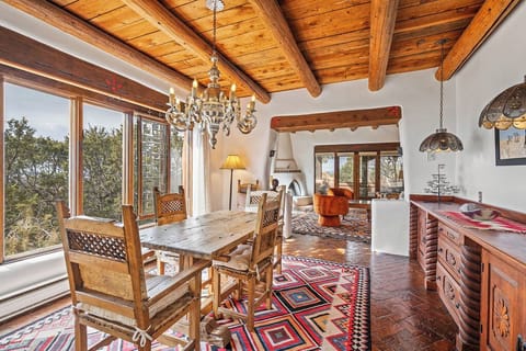 Step into your rustic dining room with exposed beams, handcrafted furniture, and stunning tree views through expansive windows.