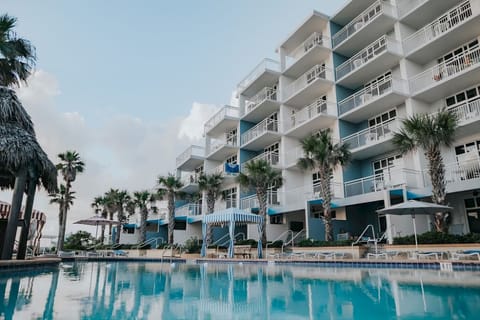 Arrive to a bright beachfront resort with balconies and palms.