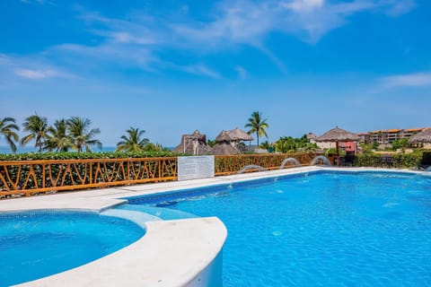 Enjoy a beautiful pool with a relaxing hot tub and ocean views just steps away. Surrounded by palm trees and lounge areas, it's the perfect spot to unwind and soak up the coastal vibe.