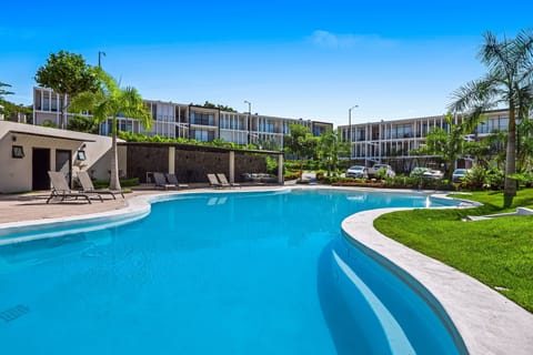 Expansive pool surrounded by palm trees, lounge chairs, and serene greenery—perfect for soaking up the sun.
