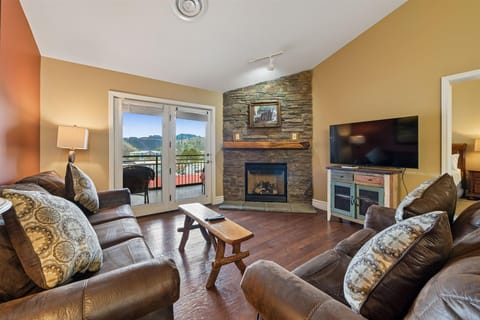 Sink into plush leather sofas by your stone fireplace, where warm light dances across rich hardwood floors and mountain views beckon through French doors.