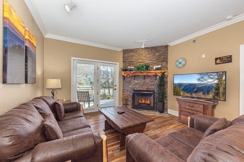 Unwind in your cozy living room with plush leather seating, crackling stone fireplace, and mountain views on the large TV.