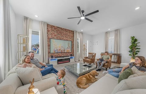 Bright and inviting living room with plush seating, a statement brick accent wall, and a mounted TV—perfect for relaxing with family.