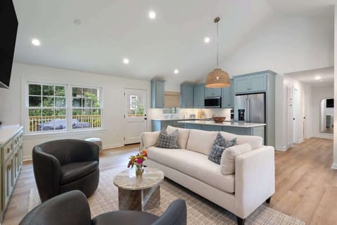Bright living room w/ cozy seating, TV & large windows bringing in natural light