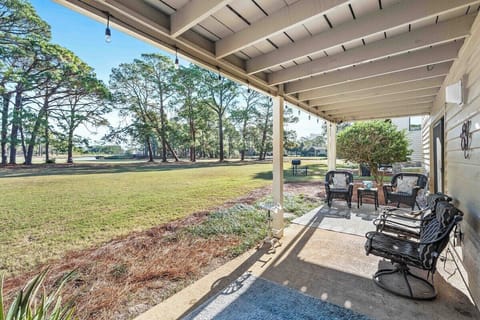 Covered back terrace with string lights, wicker seating, and sweeping golf-course views — the ideal spot to ease into the morning