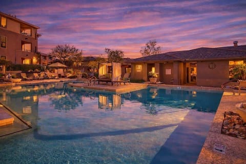 Communal Area: Sparkling blue pool and hot tub with covered cabanas, and sun loungers.
