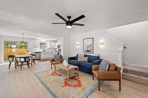 Living room: blue sofa, leather armchairs, coffee table, ceiling fan, wall art
