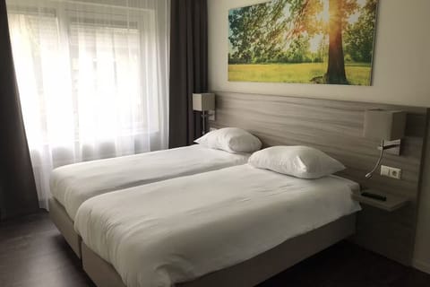 Unwind in crisp twin beds beneath soothing, sunlit artwork.