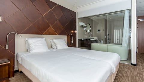 Unwind on crisp linens with a stylish open-bath backdrop.