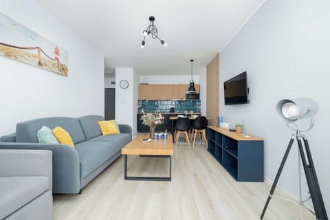 A bright living room features a comfortable grey sofa, a wooden coffee table, and a stylish tripod lamp.