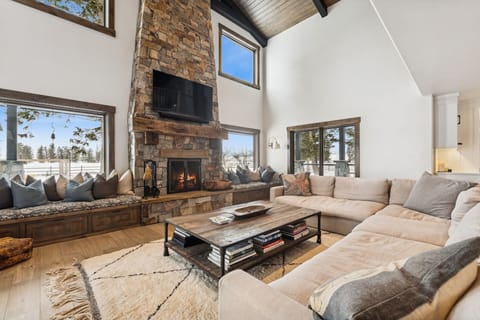 Curl up in this spacious living room where your stone fireplace crackles warmly beneath soaring ceilings and panoramic windows.