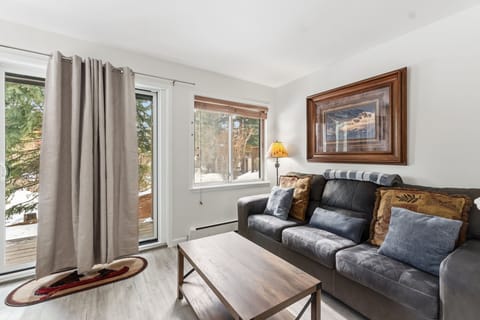 Settle into your cozy living room with plush seating and natural light streaming through large windows overlooking the peaceful winter landscape.