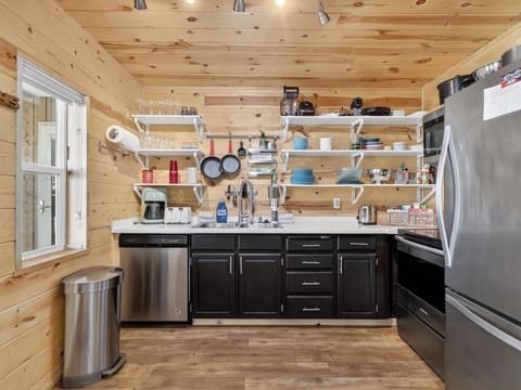 Your fully-equipped kitchen features sleek black cabinetry, stainless steel appliances, and rustic wood walls creating the perfect space for cooking memorable meals.