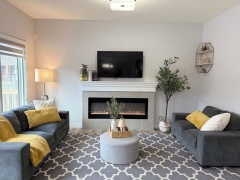 Cozy living room with 3- and 2-seater sofas, a soothing fireplace, plus books, games, and puzzles for everyone to enjoy.