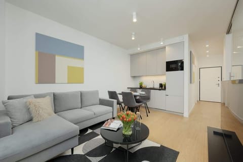 Bright living room with a gray sofa, a round coffee table, and modern wall art.