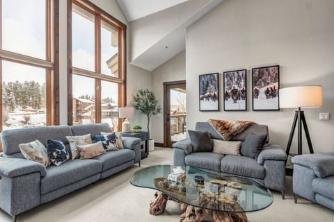 Spacious living room with vaulted ceilings, floor to ceiling windows, gas fireplace, and smart TV