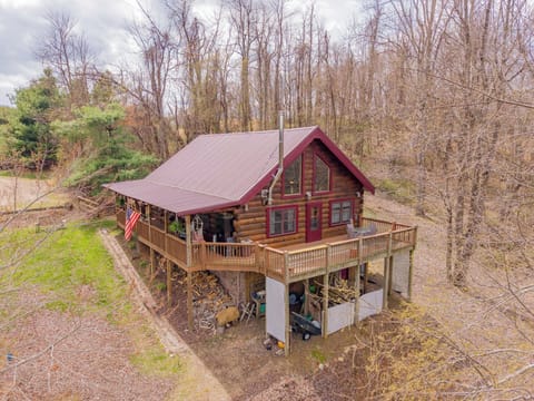 Charming log cabin with a spacious wraparound deck in a peaceful wooded setting.