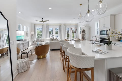 Your spacious open-concept haven blends kitchen, dining, and living seamlessly with elegant furnishings and abundant natural light streaming through oversized windows.