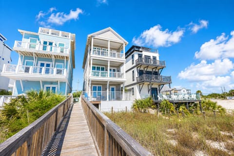 Coastal vacation homes with elevated decks and beach access via wooden boardwalk through natural dune vegetation.