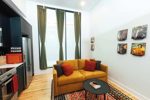 A bright and inviting living area with tall windows, bold colors, and curated décor — perfect for relaxing or entertaining.