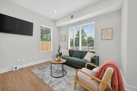 Bright and cozy living area with a smart TV, modern decor, and large windows letting in plenty of natural light.