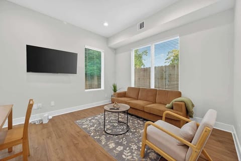 Cozy living room with wall-mounted smart TV, plush sofa seating, natural light, and modern décor—ideal for movie nights, relaxing after a day out, or unwinding in comfort.