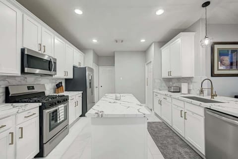 Sleek modern kitchen with white cabinetry, stainless steel appliances, and a spacious marble island