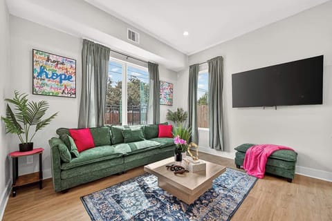 This bright and Inviting living room features a cozy green sofa, smart TV, and colorful art pieces that create a stylish, relaxing space.