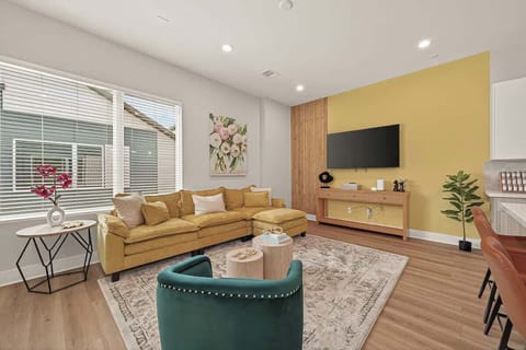 A sun-drenched space featuring a plush mustard sectional and boutique styling. Perfect for movie nights or morning coffee.